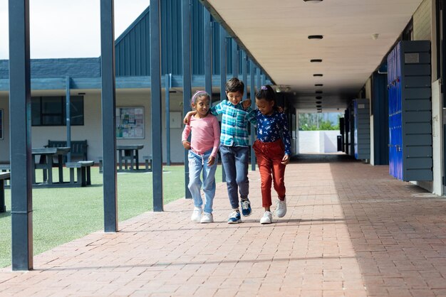 Foto três crianças biraciais estão andando juntas na escola com espaço de cópia