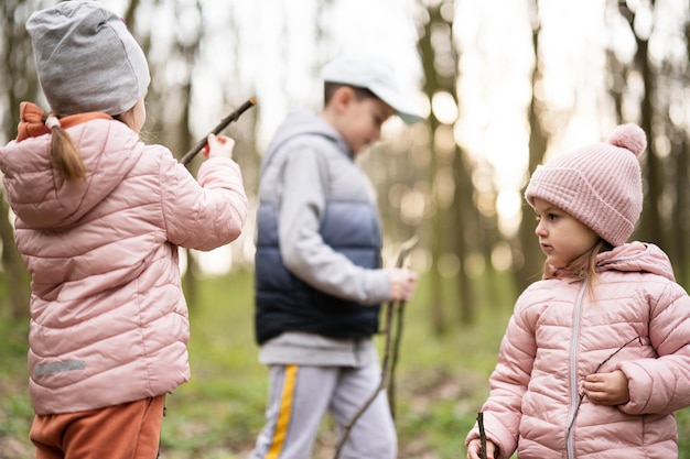 Três crianças caminhando e descobrindo a floresta da primavera Infância feliz