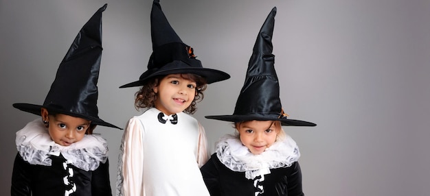 Três crianças multirraciais em fantasias assustadoras posando para um festival de Halloween