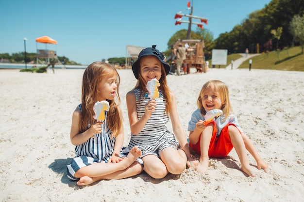 Três crianças tomam sorvete na praia uma criança com síndrome de down leva uma vida normal