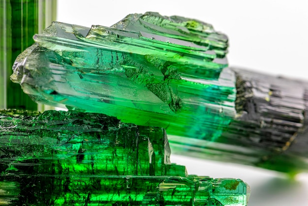 Tres cristales crudos de turmalina verde brasileña con fondo blanco