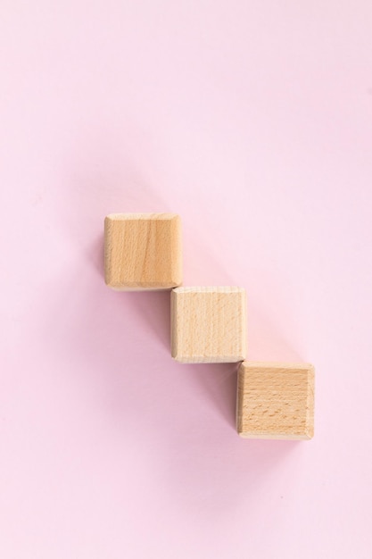 Tres cubos de formas geométricas de madera aislados en un rosa
