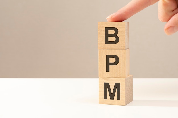 Tres cubos de madera con las letras BPM en la superficie brillante de una mesa blanca