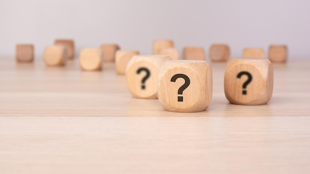 Tres cubos de madera con signos de interrogación sobre un fondo gris claro con espacio de copia desenfocado