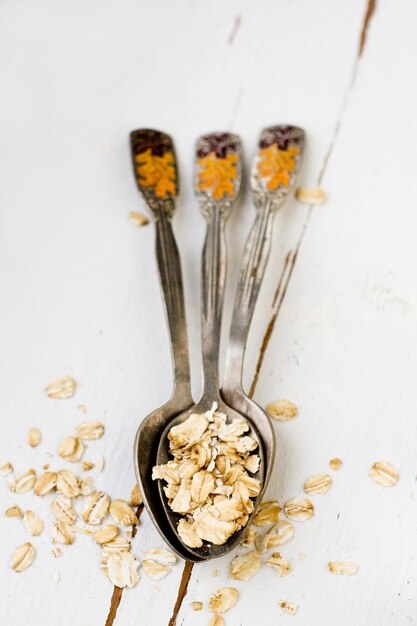 Tres cucharadas de avena acostada sobre una madera blanca Comida sana.