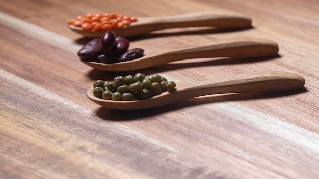 Tres cucharas de madera con legumbres de diferentes tipos frijoles lentejas rojas y soja