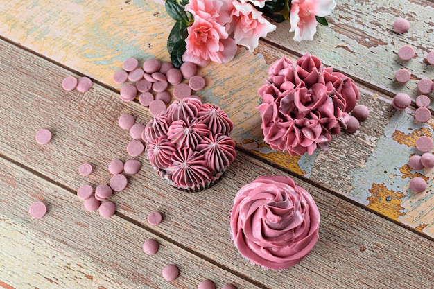 Tres cupcakes de chocolate con crema de mantequilla rosa. Junto a callets de chocolate Ruby.