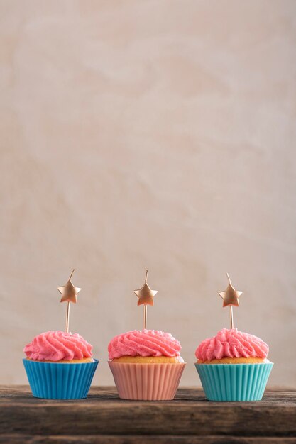 Três cupcakes festivos decorados com creme e velas. Bolinho de aniversário. Bolinho de festa. Copie o espaço.