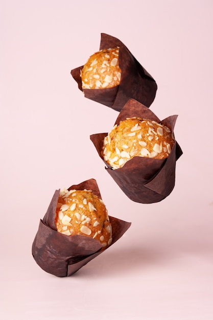 Foto tres cupcakes voladores con almendras sobre un fondo beige