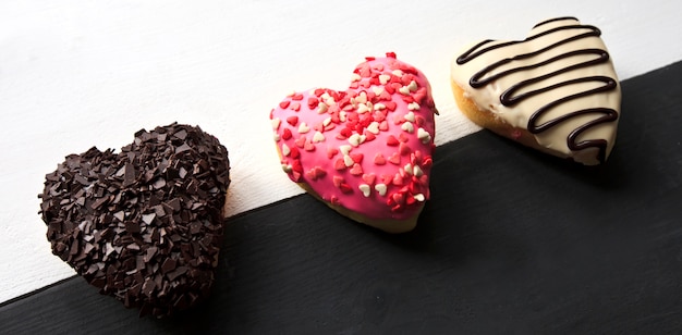 Tres deliciosas donas en forma de corazón sobre la mesa de madera