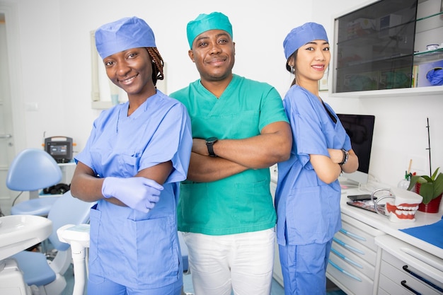 Três dentistas posam sorrindo em um consultório odontológico no setor de saúde