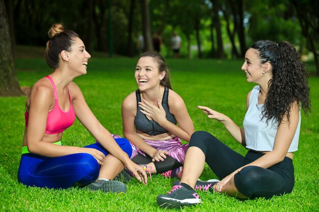 Tres deportistas riendo sobre hierba con las piernas cruzadas