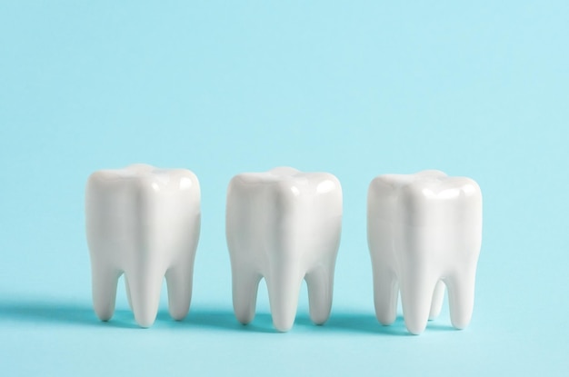 Tres dientes en fila en un cartel publicitario de una clínica de odontología de fondo azul