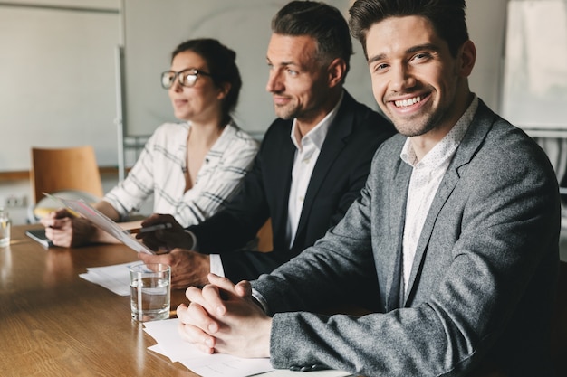 Três diretores executivos ou gerentes em ternos formais sentados à mesa no escritório e entrevistando novos funcionários para o trabalho em equipe - conceito de negócios, carreira e colocação