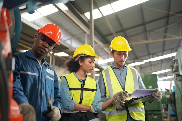 Três diversos engenheiros e trabalhadores multiculturais da indústria pesada em uniforme na fábrica de aço