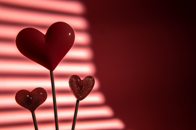 Três doces de pirulito em formato de coração rosa dia dos namorados em fundo de papel pastel vazio conceito de amor