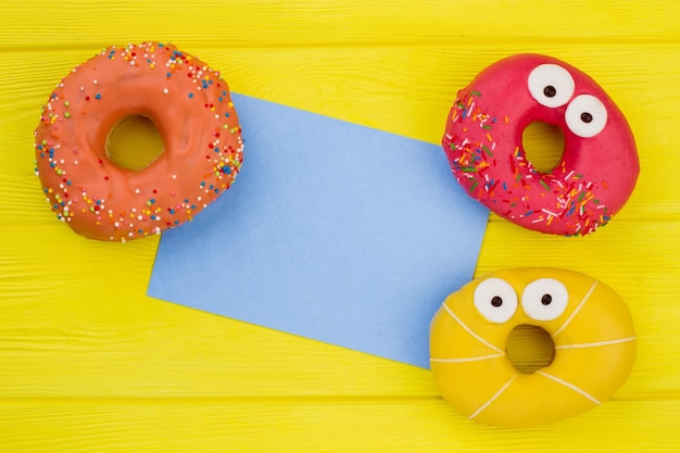 Tres donuts y tarjeta de papel en blanco.