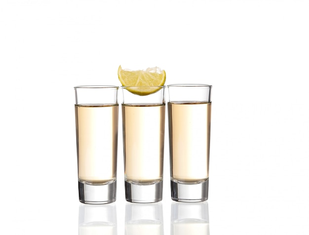 Três doses de tequila ouro com limão isolado no branco