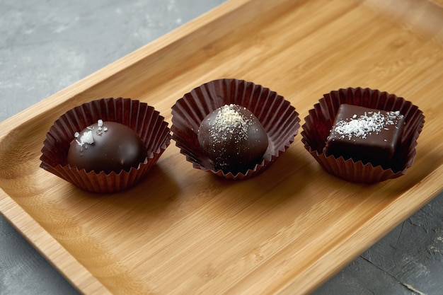 Tres dulces de chocolate diferentes sobre una tabla de madera. De cerca, enfoque selectivo