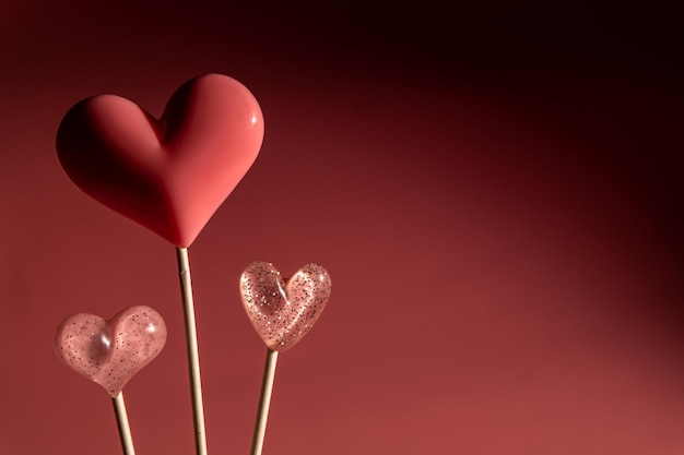 Tres dulces de paleta de forma de corazón de San Valentín rosa sobre fondo de papel pastel vacío Concepto de amor