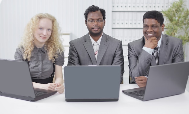 Tres empleados sentados en el lugar de trabajo en la oficina.