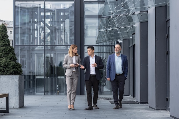 Tres empresarios diversos caminando y hablando enfocados y pensativos seriamente fuera de la oficina