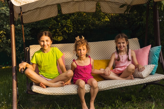 Tres encantadoras hermanas en un suave columpio de jardín