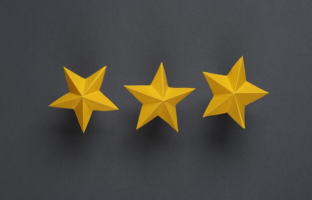 Tres estrellas de papel en fondo gris Clasificación del servicio
