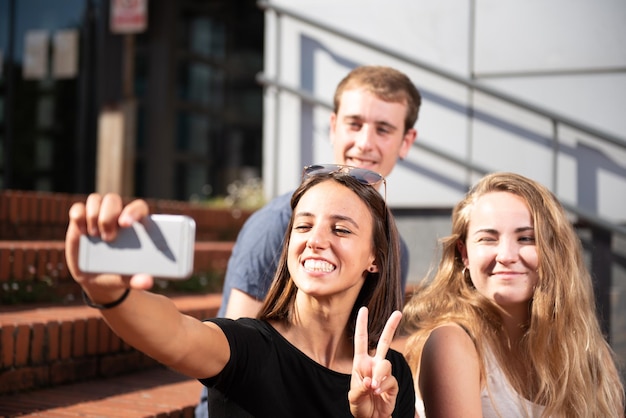 Três estudantes universitários felizes sorrindo e tirando uma selfie
