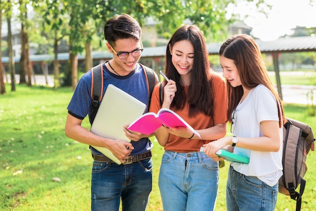 Tres estudiantes asiáticos jóvenes del campus disfrutan de la tutoría y la lectura de libros juntos