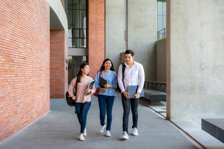 Foto tres estudiantes están caminando y hablando juntos en la sala de la universidad.