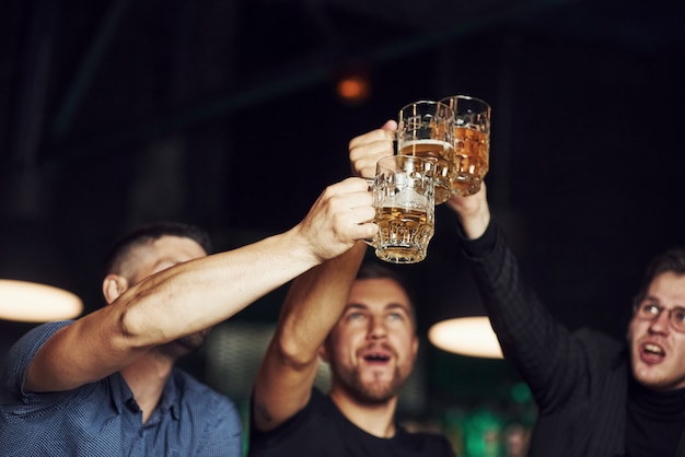 Três fãs de esportes em um bar assistindo futebol