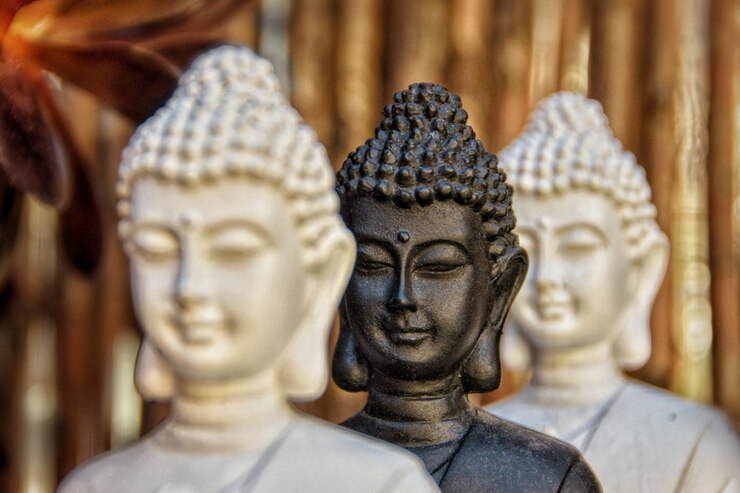 Foto três figuras de buda seguidas em um jardim.