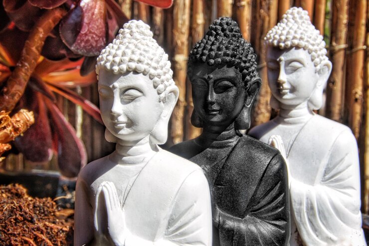 Foto três figuras de buda seguidas em um jardim.
