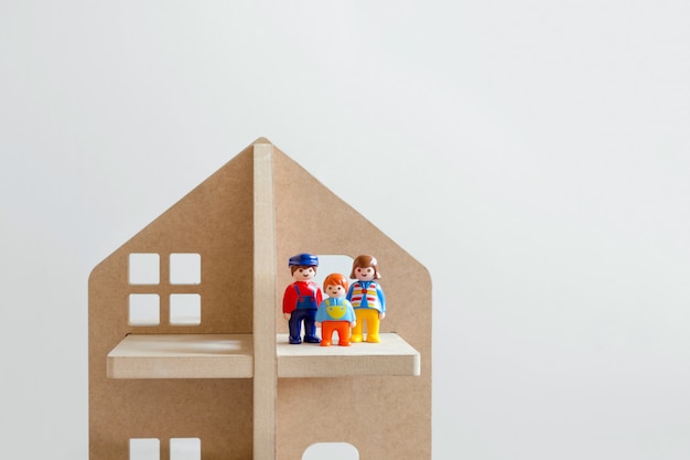 Foto tres figuras de juguete de hombres: un hombre, una mujer y un niño en una casa de juguete de madera.