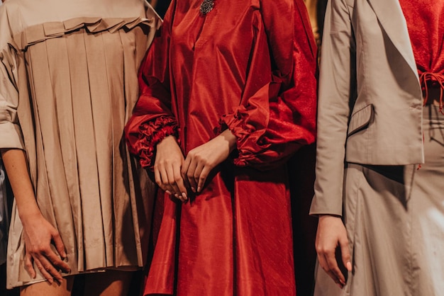 Tres figuras de la moda femenina en rojo y beige trajes casuales elegantes pantalones suéteres en el backstage