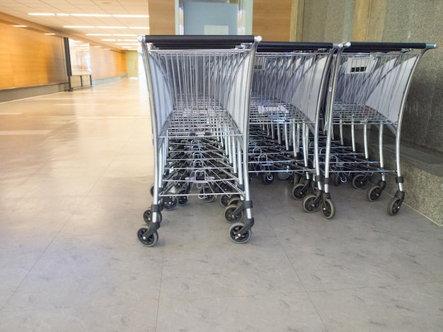 tres filas de estacionamiento de carros de equipaje en el moderno corredor del aeropuerto internacional ofrecen a todos los viajeros el uso para llevar una bolsa grande.