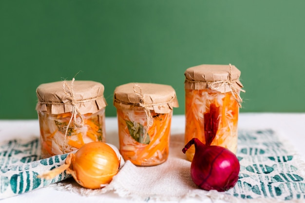 Tres frascos de chucrut y zanahorias en su propio jugo con especias, mesa de madera blanca. plato tradicional fermentado casero