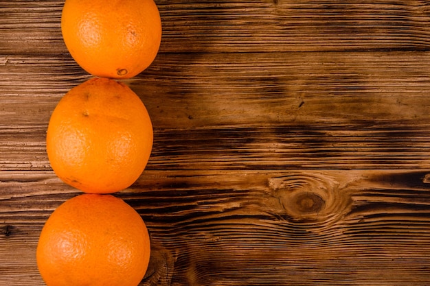 Três frutas laranja na mesa de madeira rústica vista superior