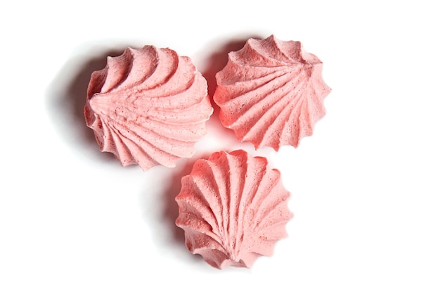 Foto tres galletas de merengue merengues besos en color rosa aislado sobre fondo blanco.