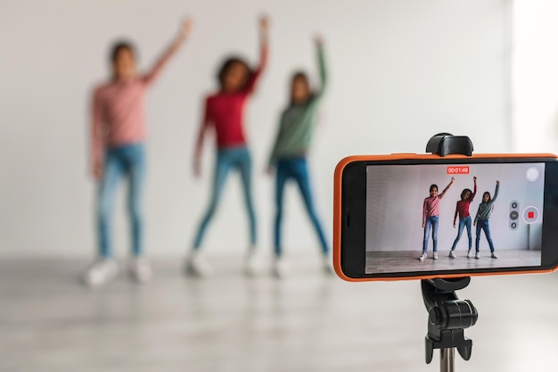 Três garotas blogueiras posando fazendo vídeo por telefone dentro de casa