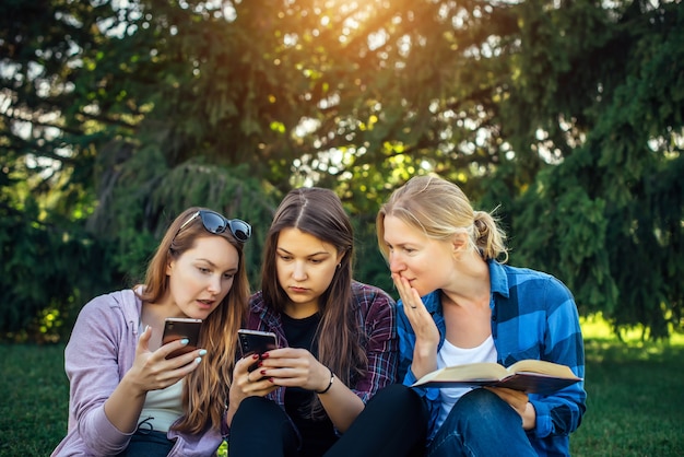 Três garotas lindas relaxam e socializam no gramado do parque de verão