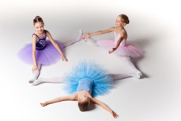 Três garotinhas de balé sentadas em tutu e posando juntas