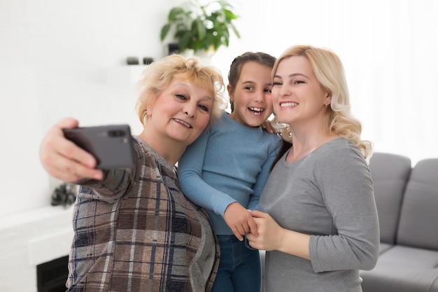 Tres generaciones de mujeres. Hermosa mujer y adolescente están besando a su abuela mientras están sentados en el sofá en casa