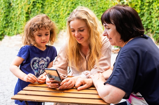 Tres generaciones de mujeres sentadas en la terraza de un café al aire libre