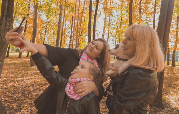 Três gerações de mulheres e cachorros se divertem olhando para a câmera posando para uma foto de autorretrato juntos