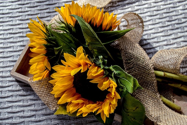 Tres girasoles en una caja de madera sobre una tela escocesa de punto