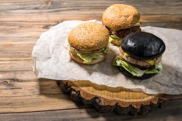 Tres hamburguesas sobre fondo de madera hamburguesas oscuras y claras