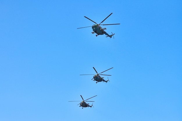 Tres helicópteros militares volando en un cielo azul brillante mientras realizan un vuelo de demostración, copie el espacio. Equipo acrobático realiza vuelo en air show