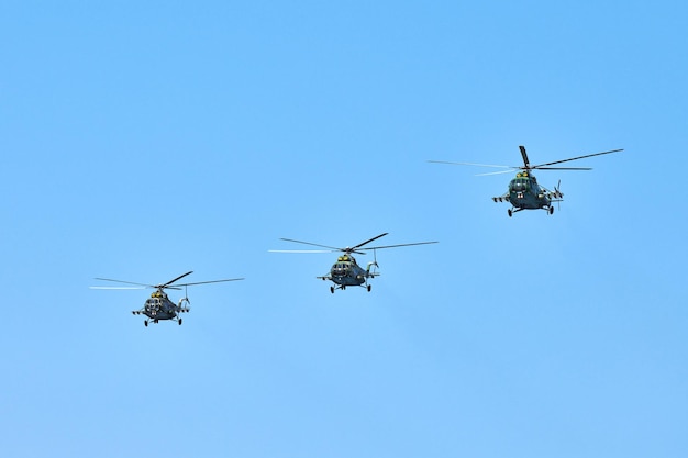 Tres helicópteros militares volando en un cielo azul brillante mientras realizan un vuelo de demostración, copie el espacio. Equipo acrobático realiza vuelo en air show